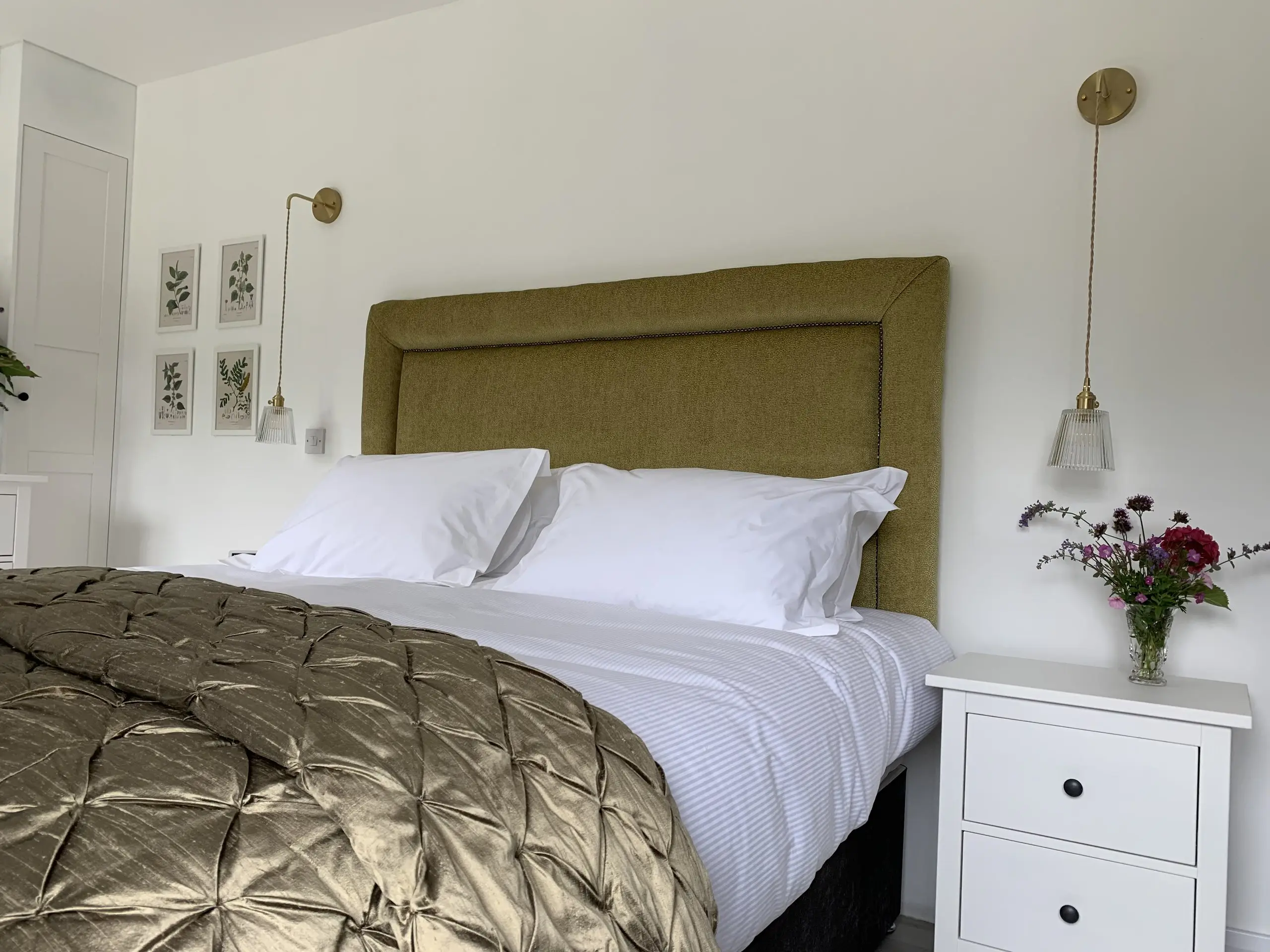 The Garden Bedroom: a super-king bed with an olive headboard and quilted throw, white linen, and a chest of drawers beside it.