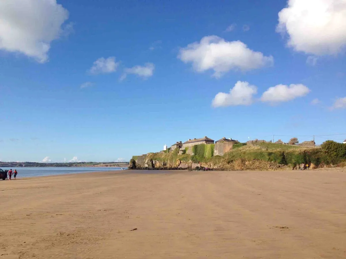Duncannon beach: a broad flat strand at low tide, with Duncannon Fort standing on the green headland beyond.
