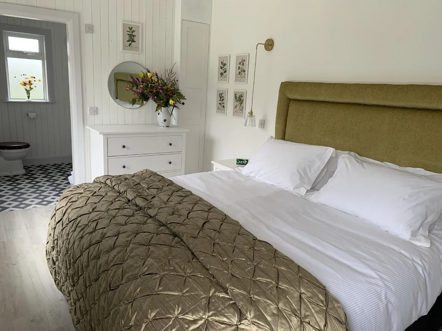 The Garden Bedroom: a super-king bed with white linen and a quilted olive throw, against white panelled walls, with a dressing table and mirror.