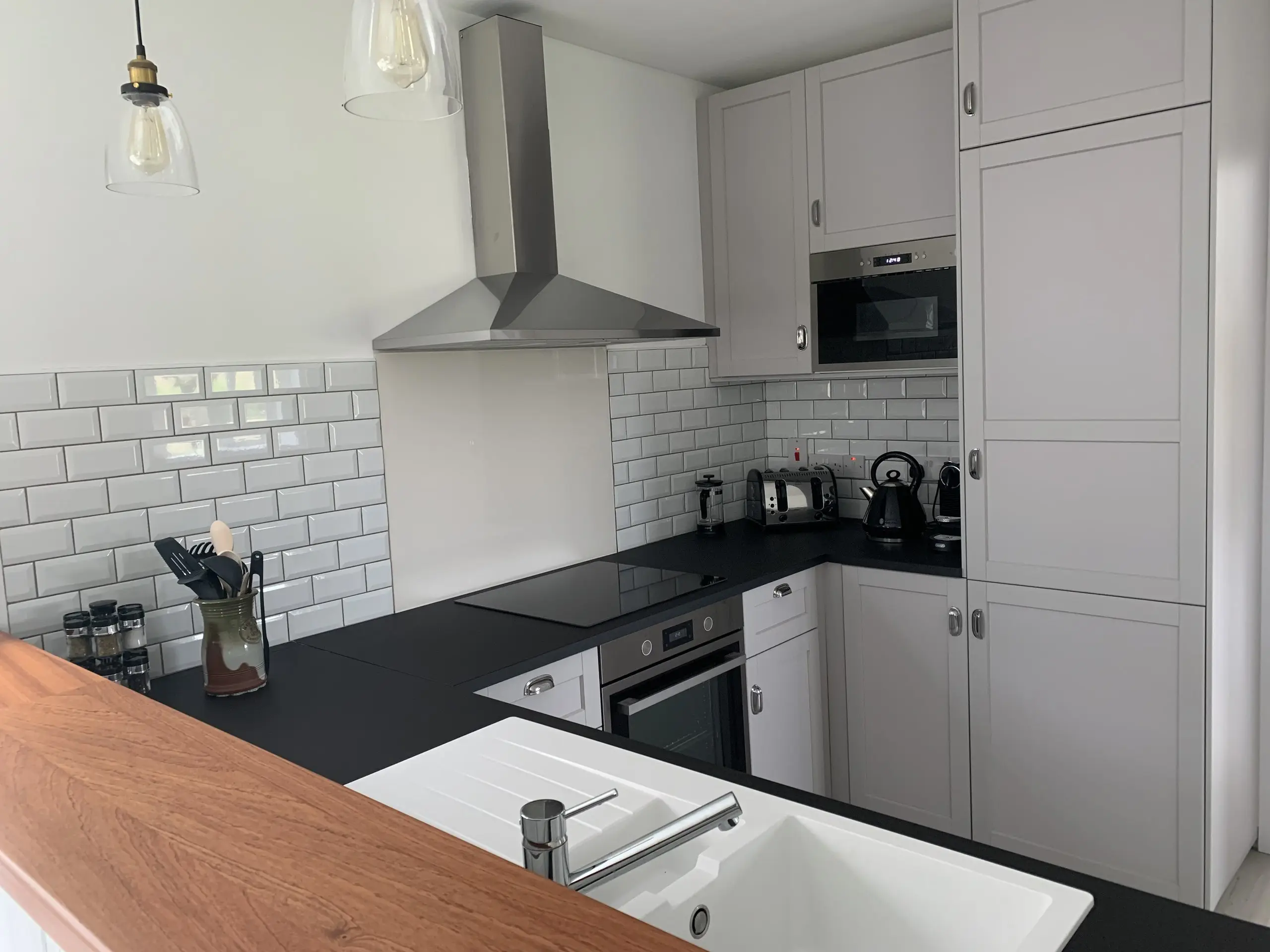 The kitchen: white units and metro tiling, dark worktops, an integrated oven and extractor, and a sink.