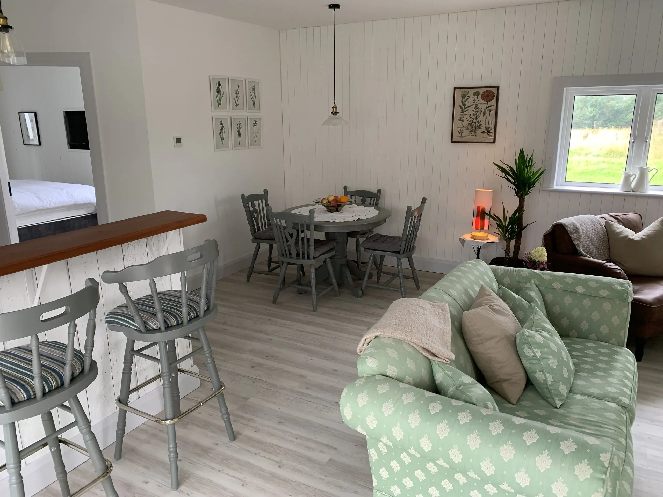 The open-plan living area looking through to the breakfast bar and dining table, with the green sofa in the foreground.