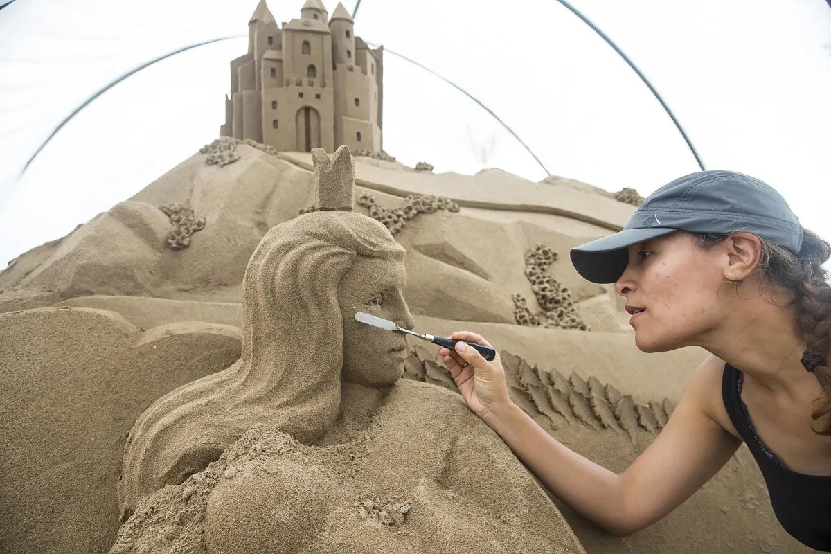A sand sculptor carving a detailed sand castle on Duncannon beach.